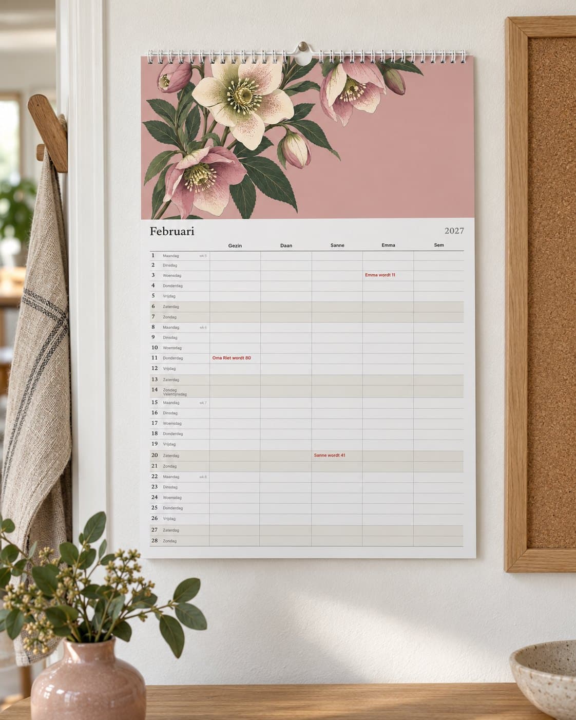 De familiekalender met een kolom per persoon, aan de muur in de keuken