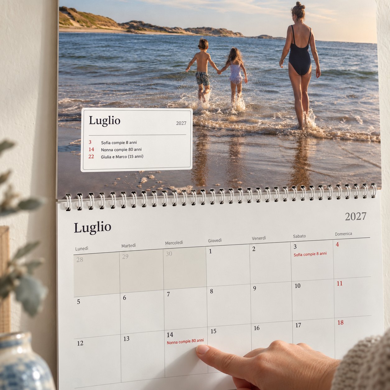 Primo piano del calendario con foto: il riquadro del mese mostra chi festeggia, e un dito indica gli 80 anni della nonna