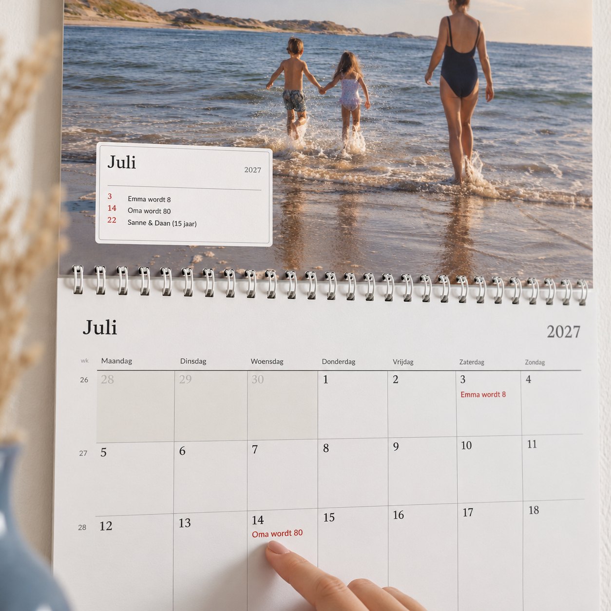 Close-up van de fotokalender: het vak van de maand toont wie er jarig is, en een vinger wijst naar oma’s 80e verjaardag